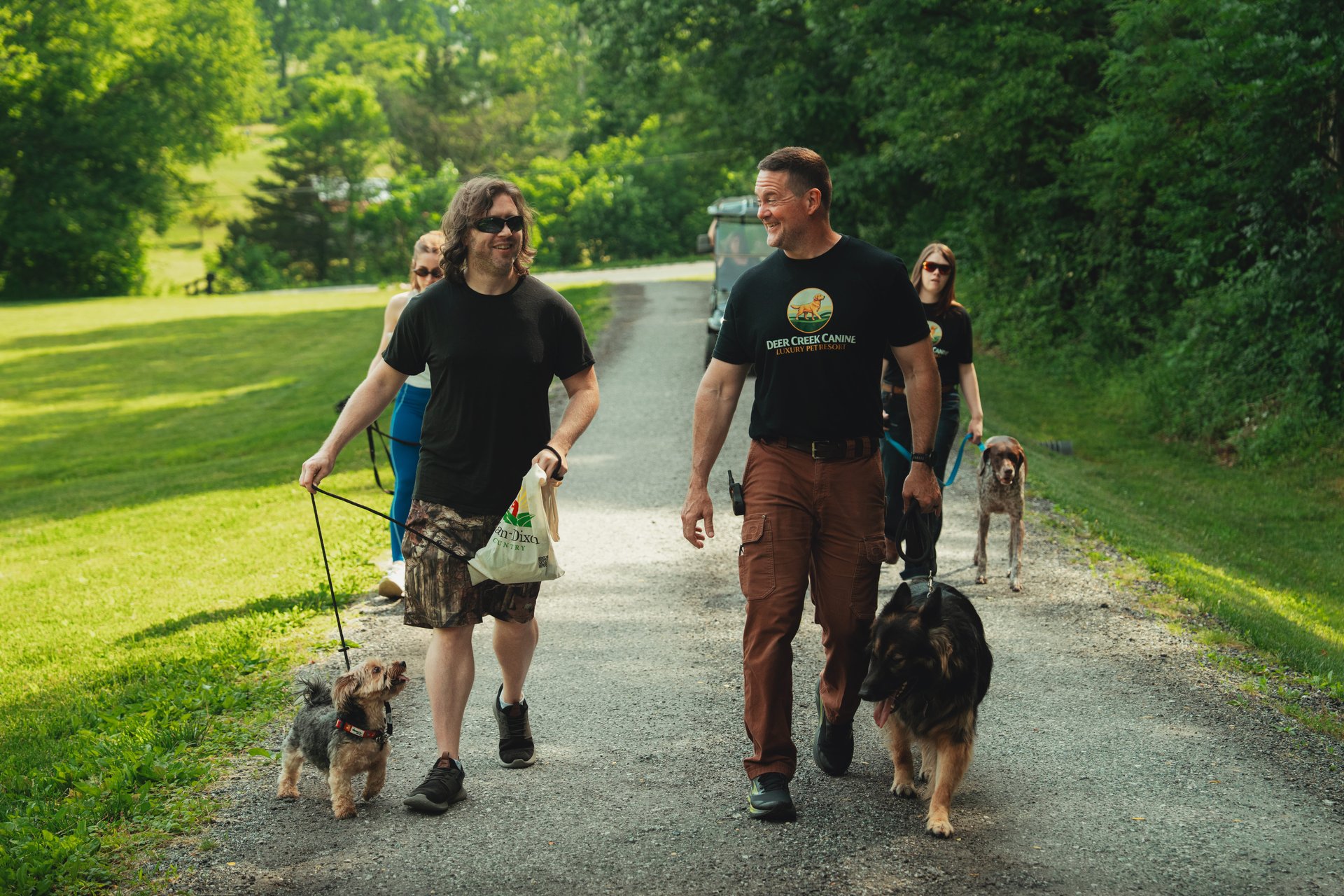 A Deer Creek Canine trainer walking well-behaved dogs on flat collars and leashes on the 23-acre Bel Air, MD resort